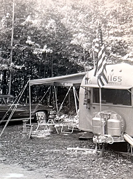 The camper in camp, flag flying.